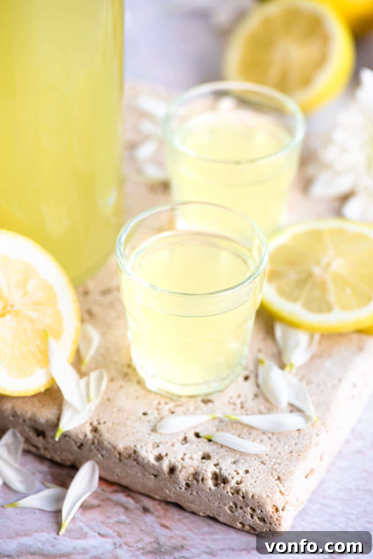 Zesty Homemade Limoncello Made Easy 6 Two shot glasses filled with limoncello with slices of lemon at the side