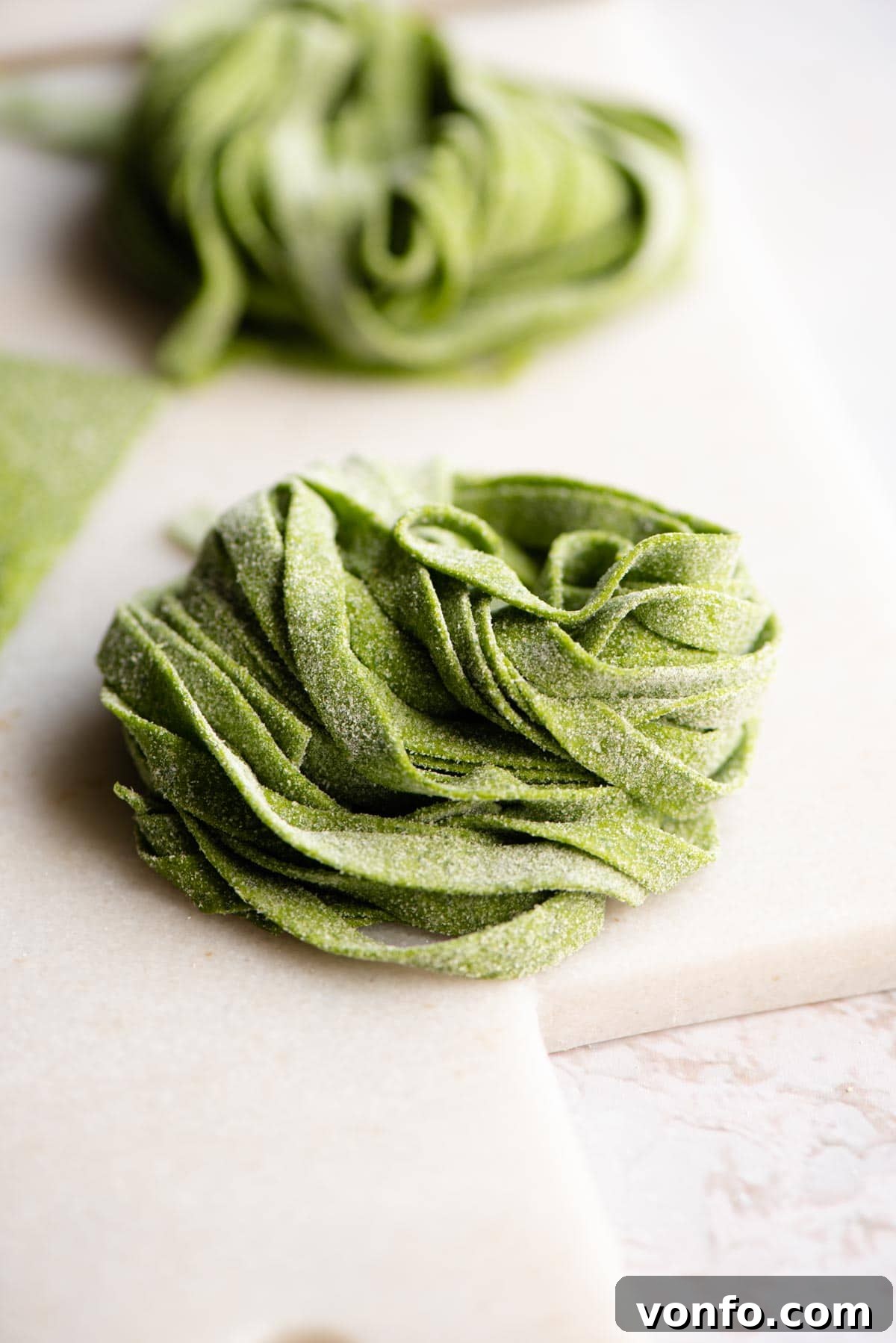 Easy Two-Ingredient Spinach Pasta Dough 8 A close-up shot of uncooked, fresh spinach tagliatelle, showcasing its vibrant green color and perfect texture.