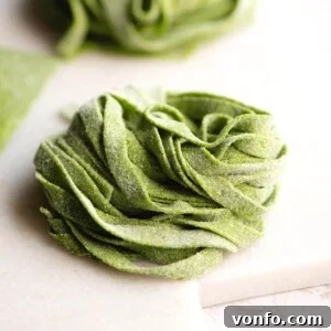 A close up of spinach pasta tagliatelle on a marble cutting board