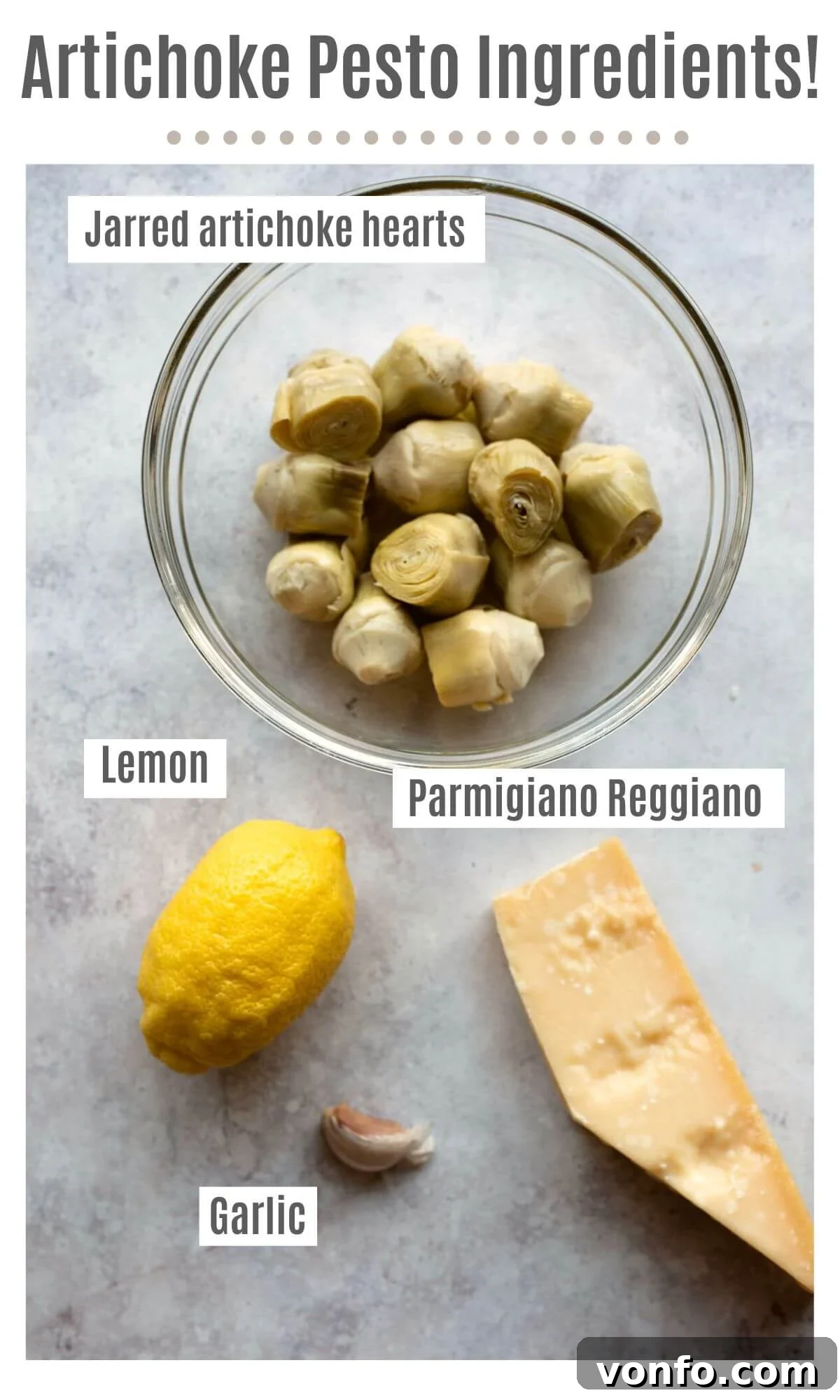 An overhead shot of labelled ingredients needed to make artichoke pesto; jarred artichoke hearts, lemon, Parmigiano Reggiano and garlic.