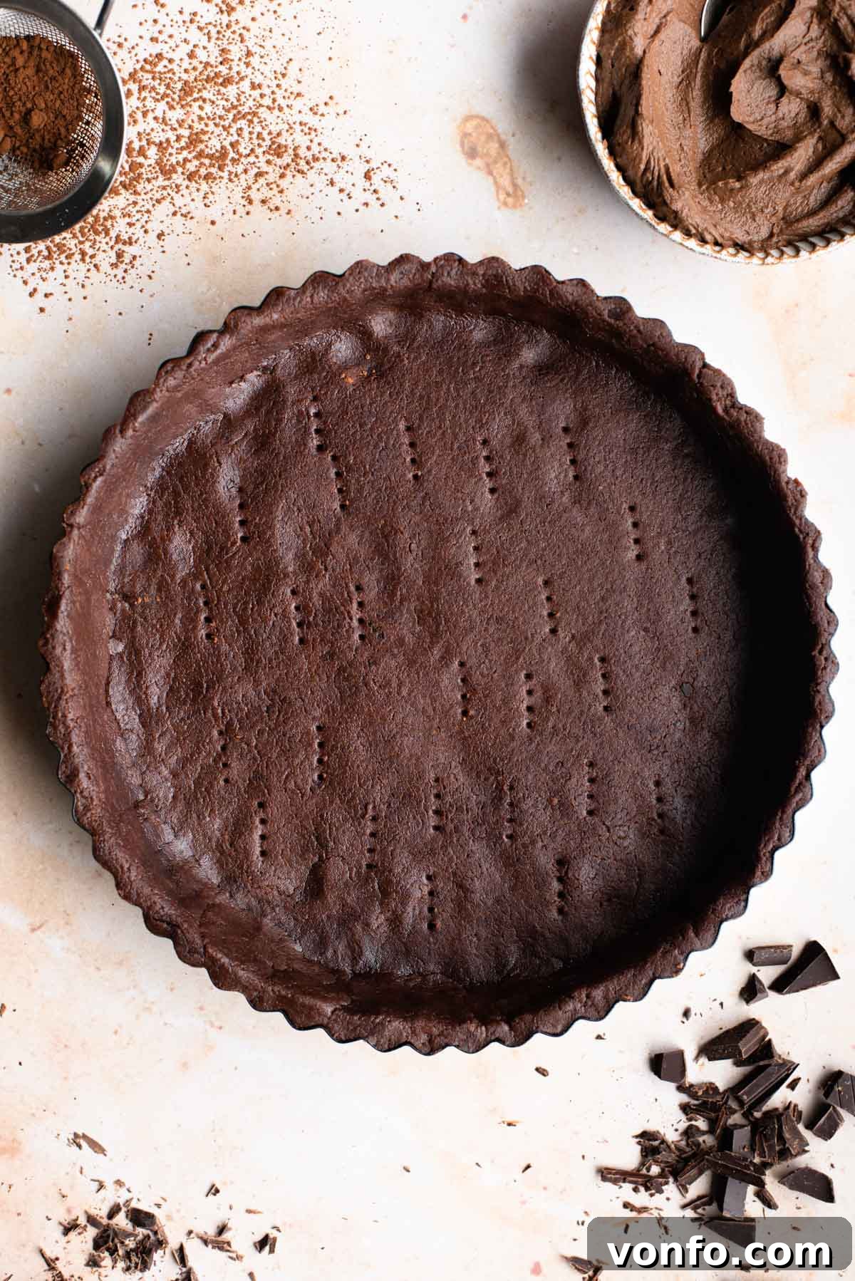 An overhead shot of chocolate pastry in a tart pan ready to be baked, showcasing its rich, dark color and smooth texture
