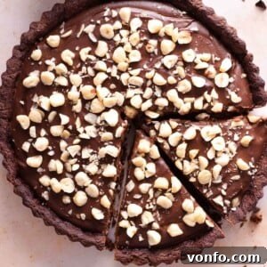 A close up of a chocolate tart topped with chopped hazelnuts