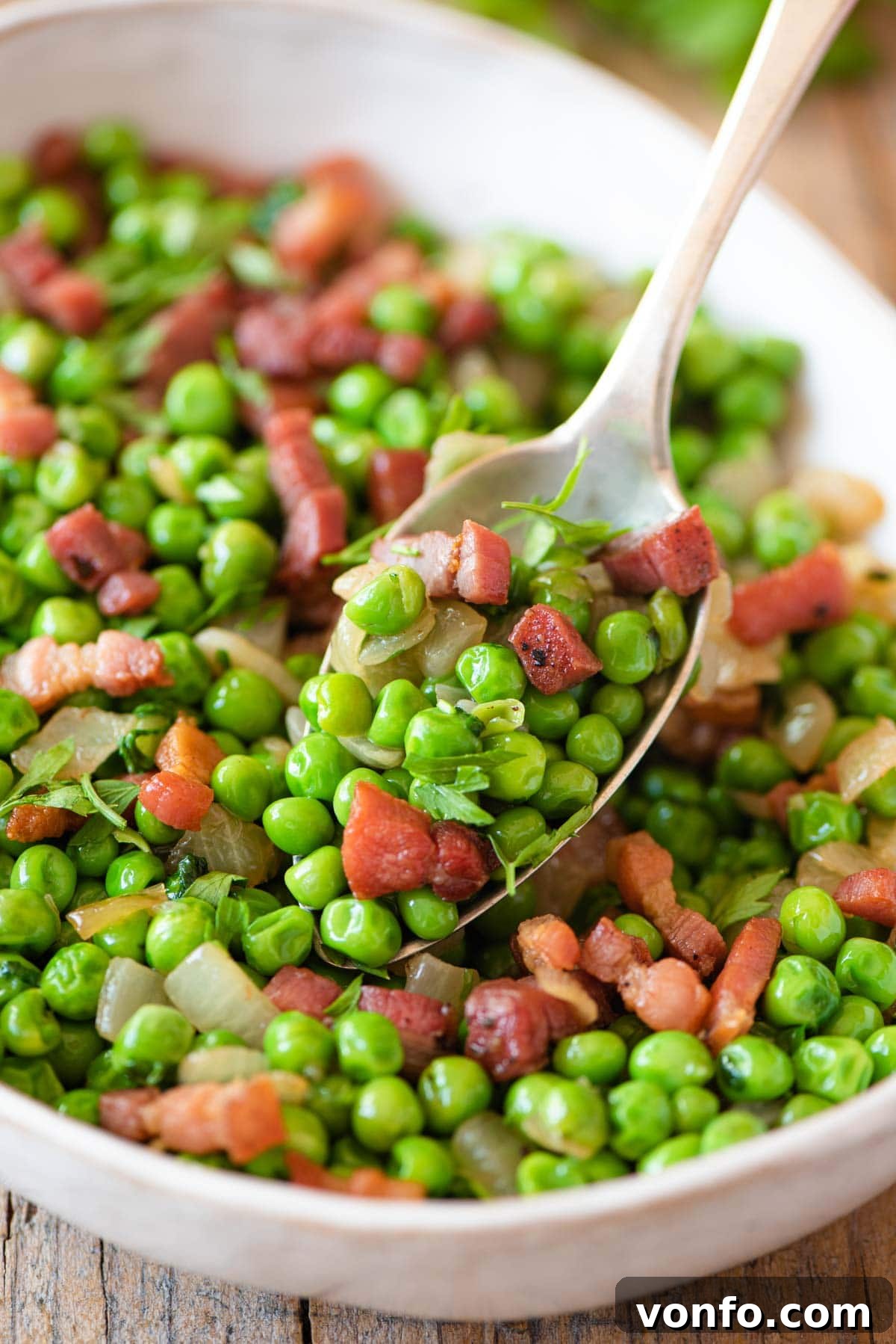 Italian Peas with Crispy Pancetta 6 A close up of vibrant green peas and crispy golden pancetta on a spoon, ready to be enjoyed