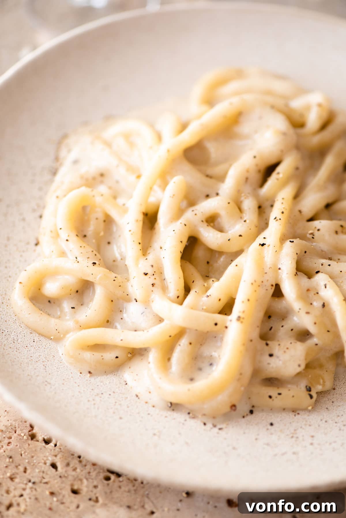 Pici Cacio e Pepe Simple Roman Perfection 6 A close up of pici pasta with cacio e pepe sauce on a plate