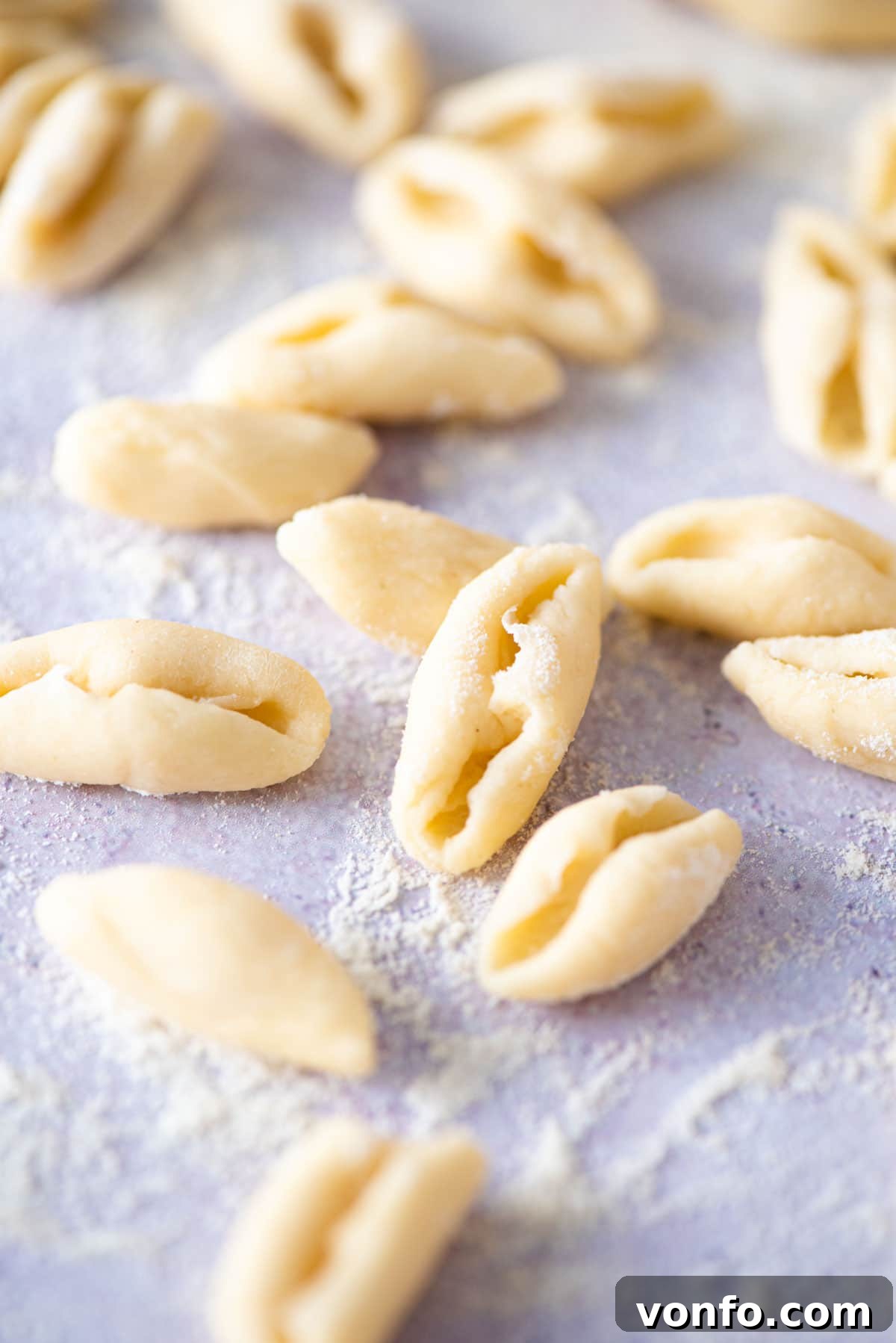 A close-up shot of perfectly shaped, fresh cavatelli pasta waiting on a blue work surface.