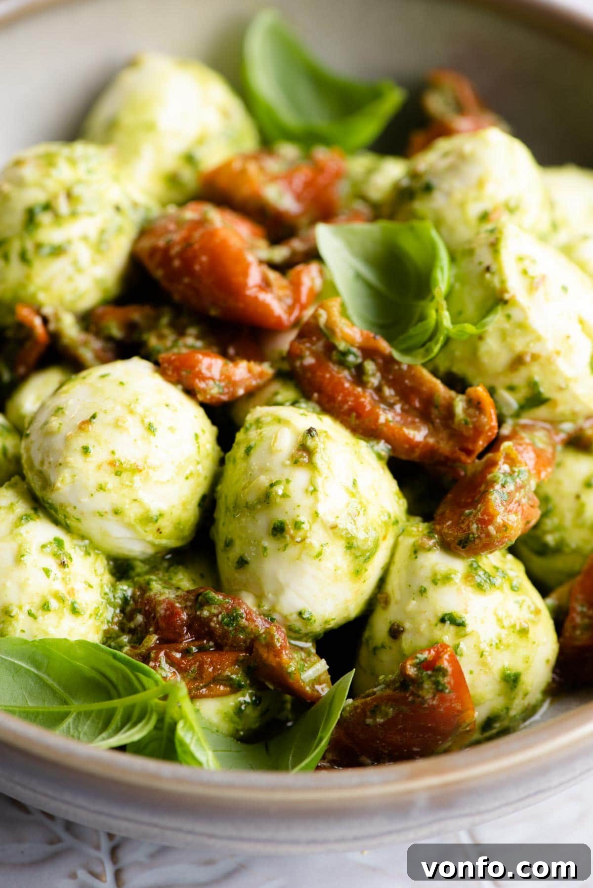 Pesto Bocconcini with Sun-Blushed Tomatoes 5 A mesmerizing close-up photograph of creamy mozzarella bocconcini balls generously coated with luscious green pesto and interspersed with sweet, sun-kissed red tomatoes, perfectly highlighting the inviting texture and vibrant color palette of the dish.
