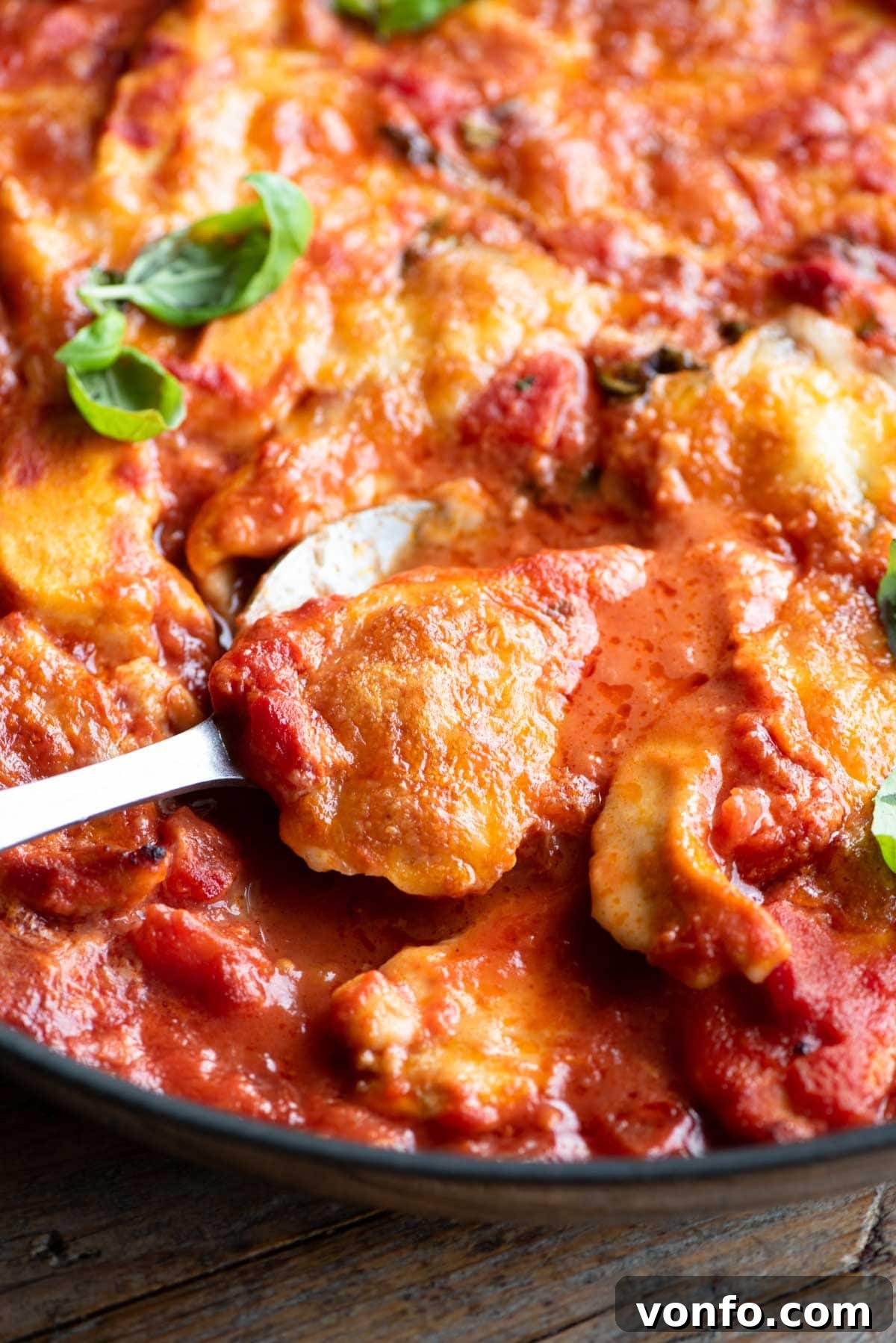 A close-up shot of a perfect piece of Chicken Sorrentina, gently scooped onto a serving spoon, showcasing the melted mozzarella and rich sauce.