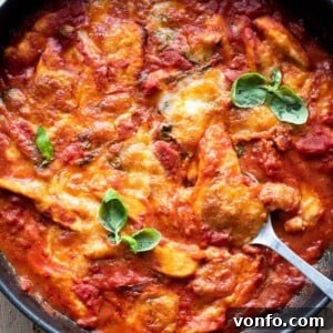 A close-up shot of Chicken Sorrentina served in a skillet, showcasing the melted cheese and rich tomato sauce.