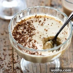 A close up of baileys panna cotta in a small glass bowl with a spoon in it