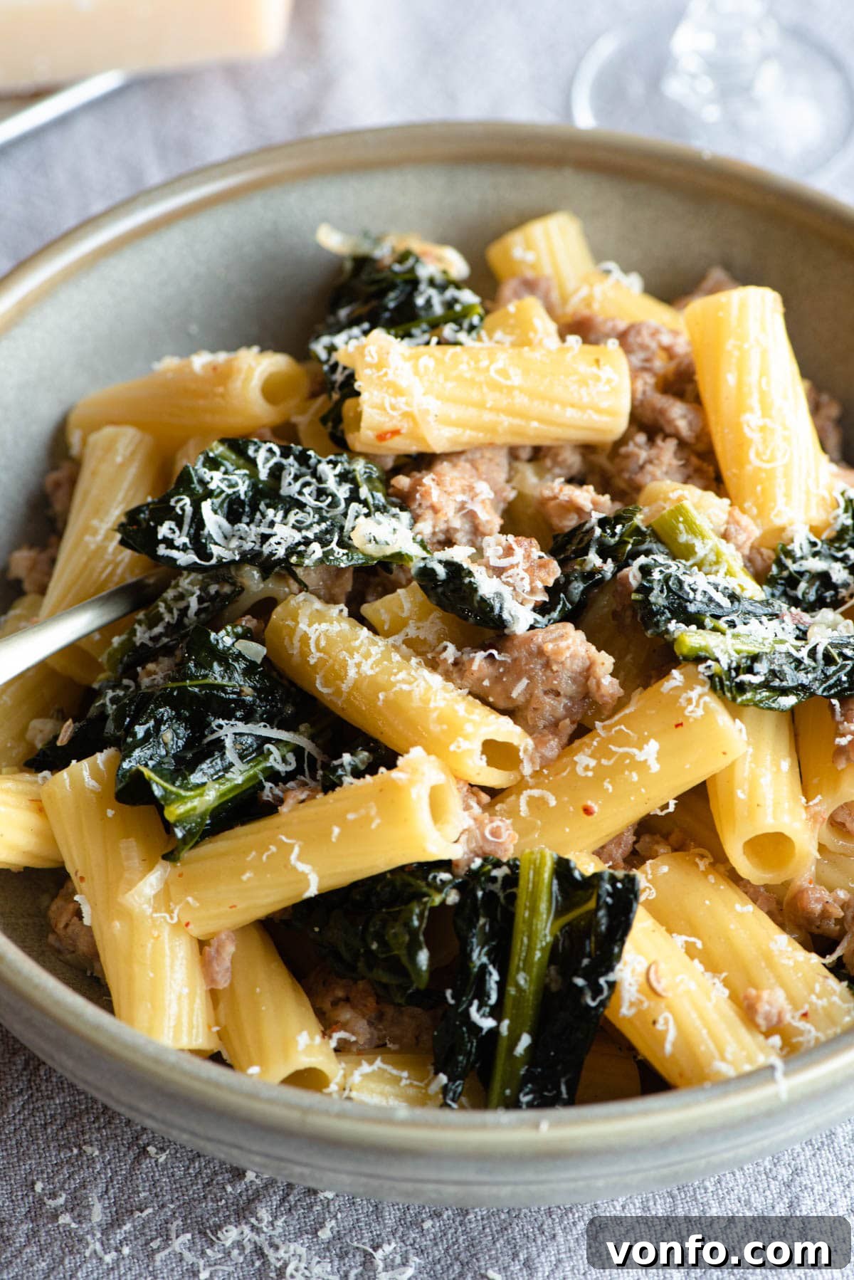 A close-up shot of perfectly cooked rigatoni pasta tossed with a rich sauce of savory Italian sausage and tender cavolo nero, ready to be served.