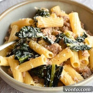 A close up of a bowl of sausage and cavolo nero pasta, showcasing the appetizing texture and garnish.