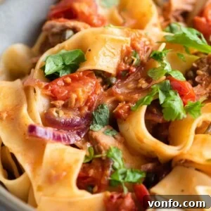 A close-up of tuna pasta with tomatoes and parsley, ready to be served.