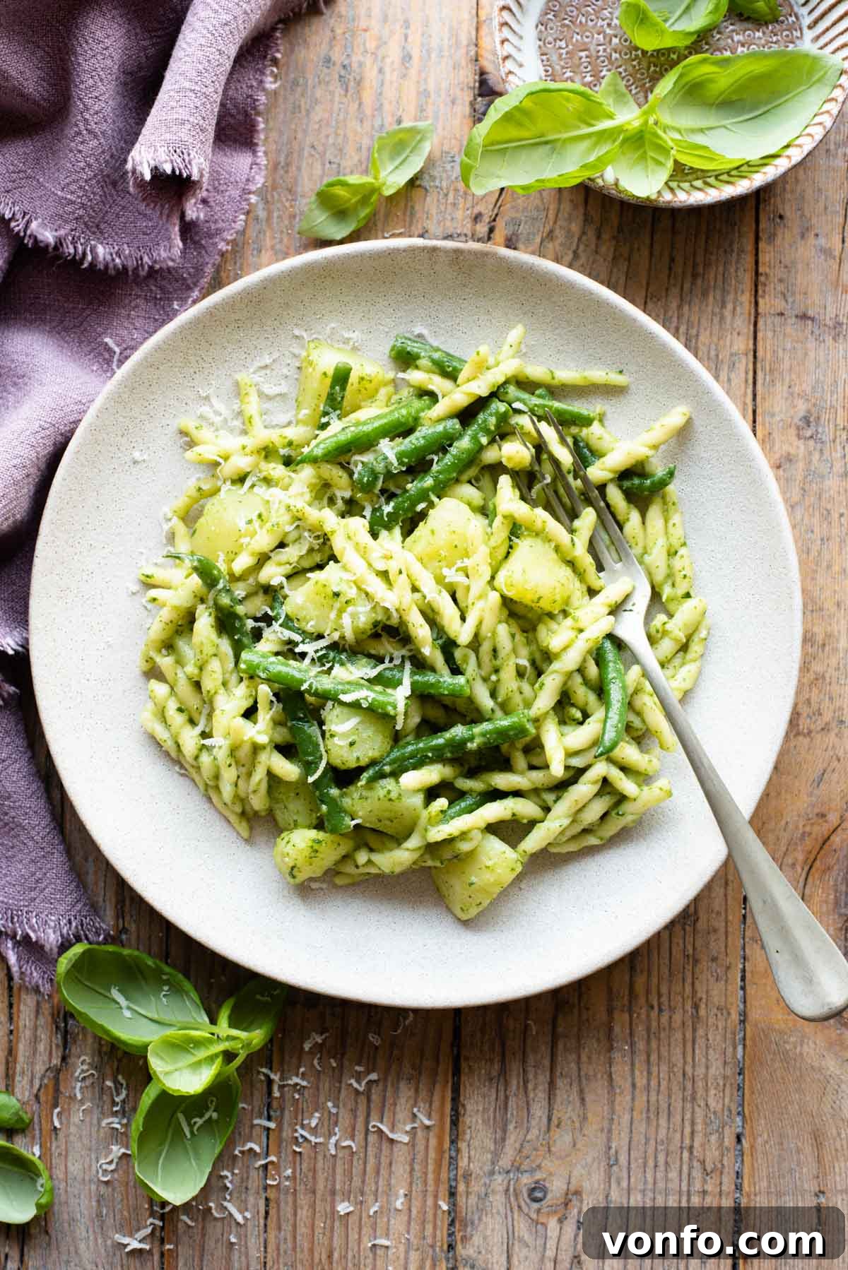 Trofie with Genovese Pesto, Hearty Potatoes, and Crisp Green Beans 2 Trofie pasta with pesto, potatoes and green beans on a plate sitting on a wooden surface