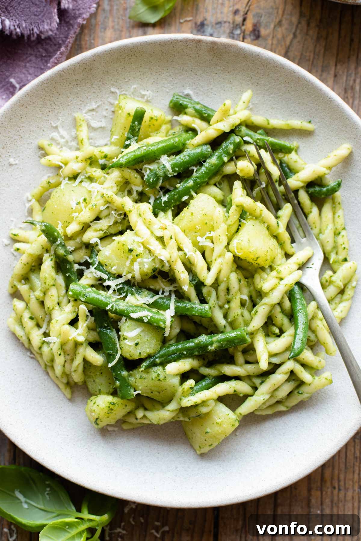 Trofie with Genovese Pesto, Hearty Potatoes, and Crisp Green Beans 6 A close up of trofie pasta with pesto, potatoes and green beans on a plate with a fork at the side