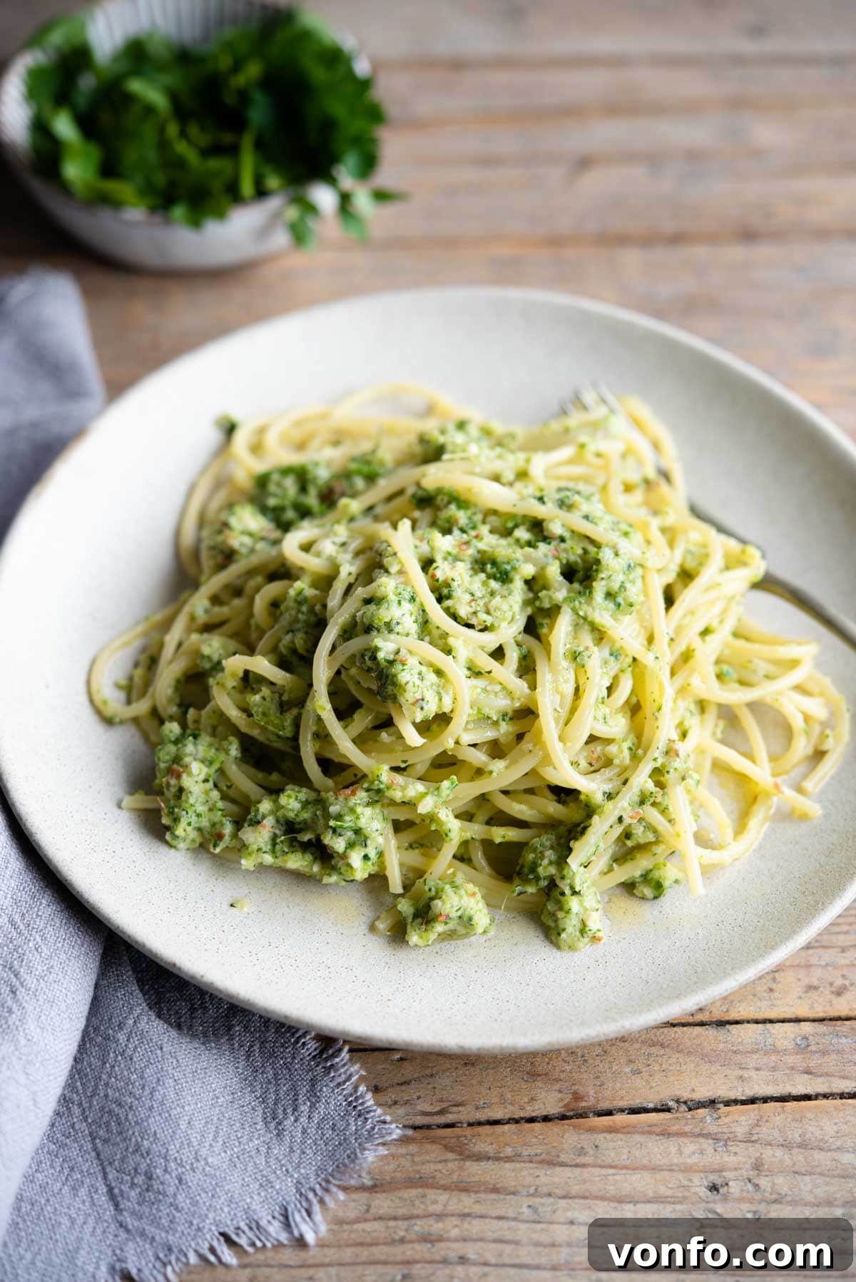 Garden Fresh Zucchini Pesto Pasta Simple and Satisfying 2 A beautifully arranged plate of Zucchini Pesto Pasta on a rustic wooden surface, accompanied by a blue linen towel.