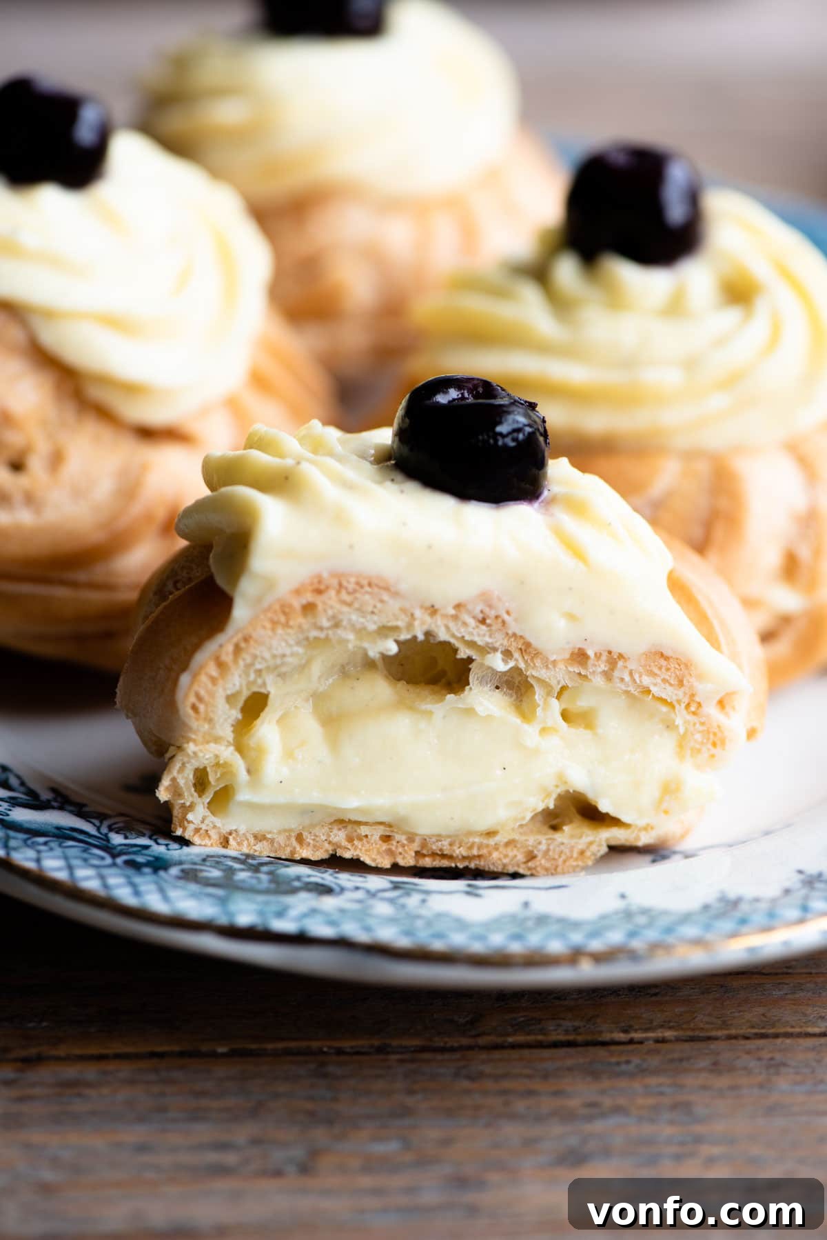 St Joseph Zeppole 9 A close up of an Italian pastry cut in half and filled with pastry cream sitting on a blue plate.