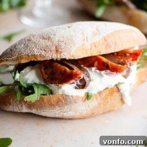Amalfi Burrata and Anchovy Sandwich 4 A close up of a ciabatta sandwich filled with arugula, burrata, anchovies and tomatoes, highlighting the rich textures and vibrant colors.