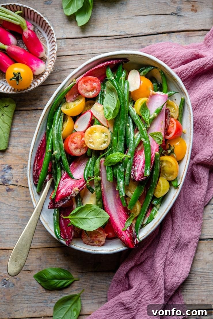 Easy Green Bean Salad with Zesty Mustard Garlic Dressing A vibrant, rustic bowl of fresh green bean salad with tomatoes, radishes, and radicchio, drizzled with a zesty mustard garlic dressing.