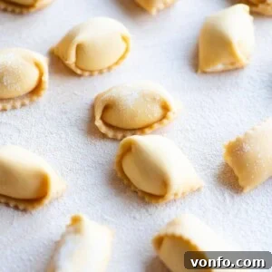 A close up cropped image of homemade Agnolotti on a wooden board, showcasing the detailed pinched edges.