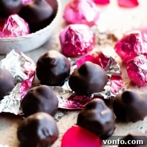 Handcrafted Italian Chocolate Kisses 5 A close-up cropped image of homemade Baci chocolates, some artfully wrapped in vibrant pink foils, resting on a luxurious travertine worktop, prepared for enjoyment or elegant gifting.