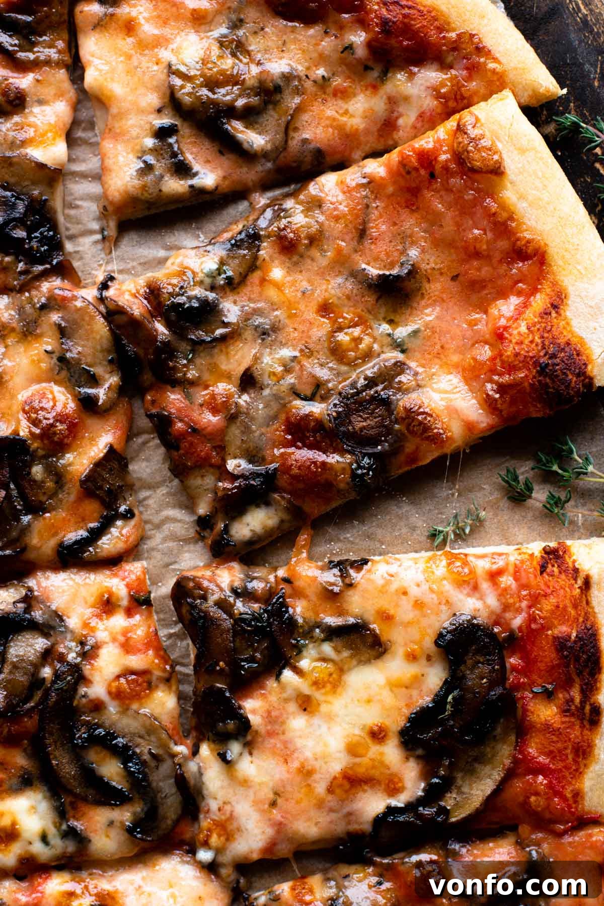 Gourmet Taleggio Mushroom Pizza 7 A close up of a mushroom pizza with taleggio cheese on a wooden surface.