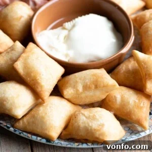 A close-up square image of Gnocco Fritto (Italian fried dough) on a plate with cheese.