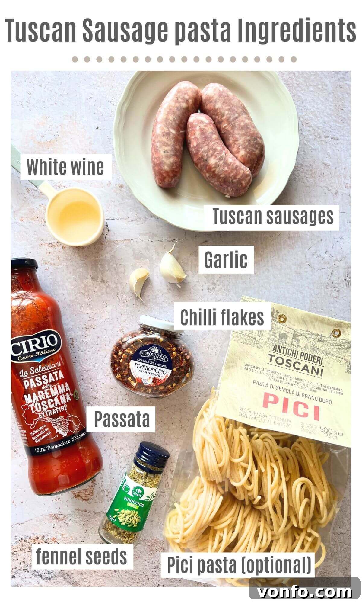 An overhead shot of all the fresh ingredients needed to make Tuscan sausage pasta, neatly arranged on a kitchen surface.
