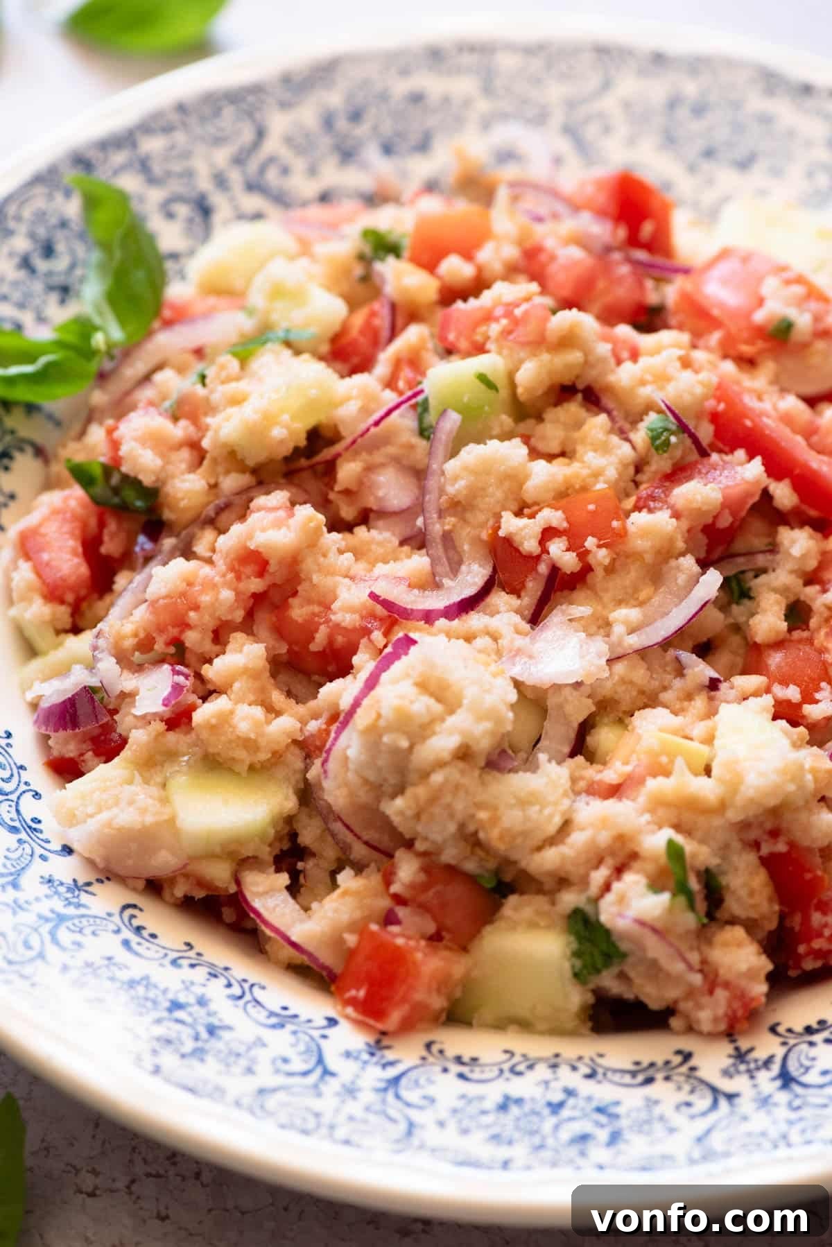 Rustic Tuscan Panzanella 5 A vibrant close-up of authentic Panzanella salad, highlighting the juicy tomatoes and basil in a blue patterned bowl.