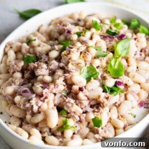 A beautifully composed white bean and tuna salad with fresh basil and lemon, ready to be served.