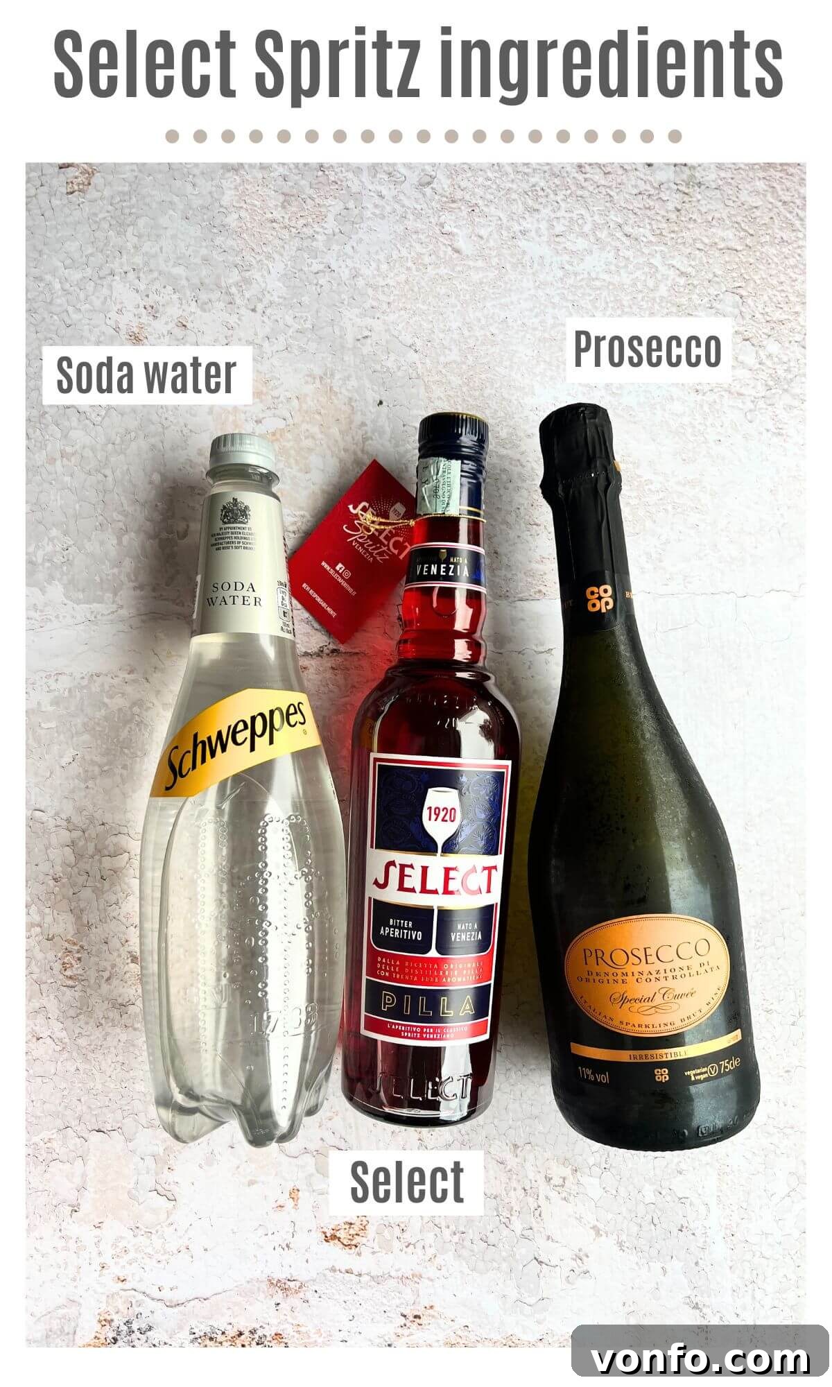 An overhead shot of all ingredients needed to make a Select Spritz cocktail, including Select Aperitivo, Prosecco, soda water, and a jar of green olives.