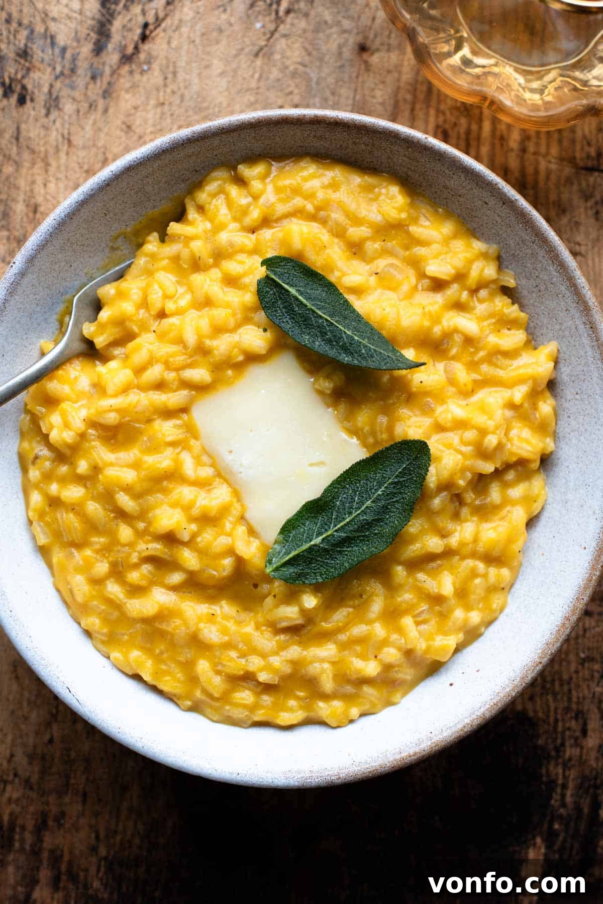 Creamy Taleggio Pumpkin Risotto, Crispy Sage Finish 2 An overhead shot of a vibrant orange Pumpkin Risotto in a rustic bowl, garnished with a generous slice of melting Taleggio cheese and delicate, crispy sage leaves. Perfect for a cozy autumn meal.