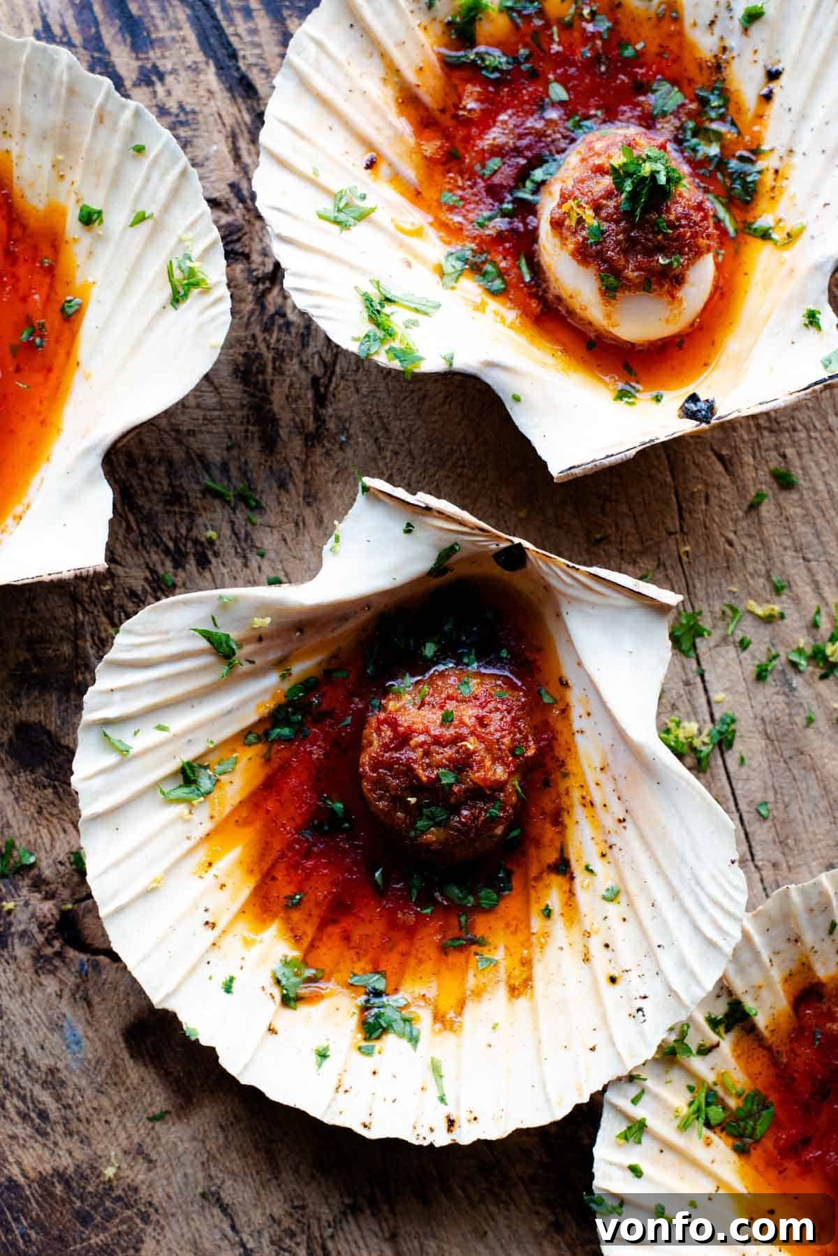 'Nduja Garlic Butter Scallops 2 An overhead shot of perfectly cooked scallops in their shells, generously topped with vibrant 'Nduja garlic butter and a sprinkle of fresh gremolata.