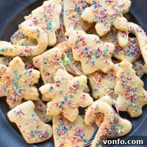 A close up cropped image of Befanini cookies on a plate with blurred colored fairy lights around, creating a warm and festive atmosphere.