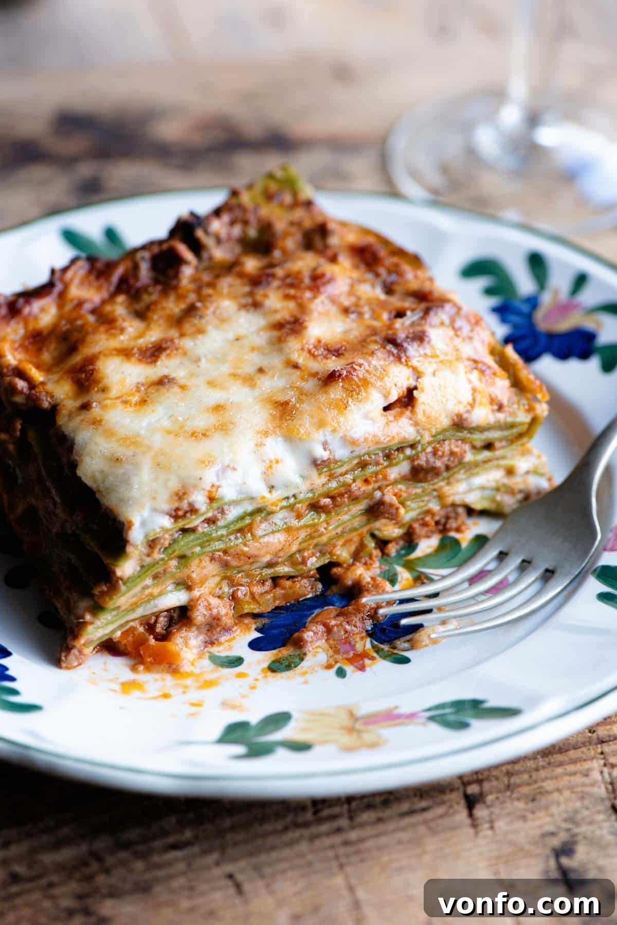 Lasagna Bolognese with creamy Besciamella sauce A close-up shot of a perfectly plated slice of Lasagna Bolognese, featuring rich layers and creamy Besciamella, adorned with a delicate flower pattern on the plate.