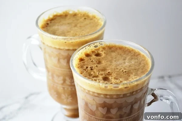 Double Delight: Banana Coffee Duo Two steaming glasses of homemade banana milk coffee, perfectly garnished, displayed on a clean white surface.