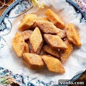 A square image of Crema Fritta (fried custard bites) in a bowl sitting on a wooden surface.