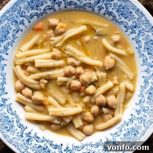 An overhead shot of Pasta e Ceci (pasta and chickpeas) in a blue bowl, garnished and ready to serve, highlighting its comforting appeal.