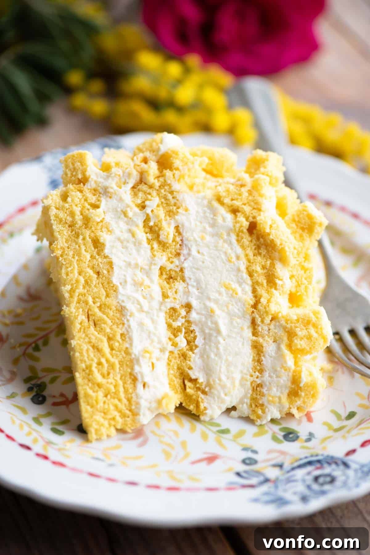 Classic Italian Mimosa Cake 14 A perfectly portioned slice of Torta Mimosa, showcasing its three layers of light sponge cake generously filled with creamy chantilly and pastry cream, resting on a small elegant plate, inviting enjoyment.