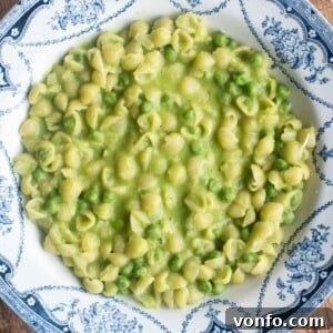 A cropped overhead shot of creamy pasta and peas in a blue patterned bowl.