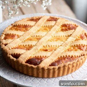 A cropped square image of a Pastiera Napoletana (Italian Easter dessert) on a cake stand.