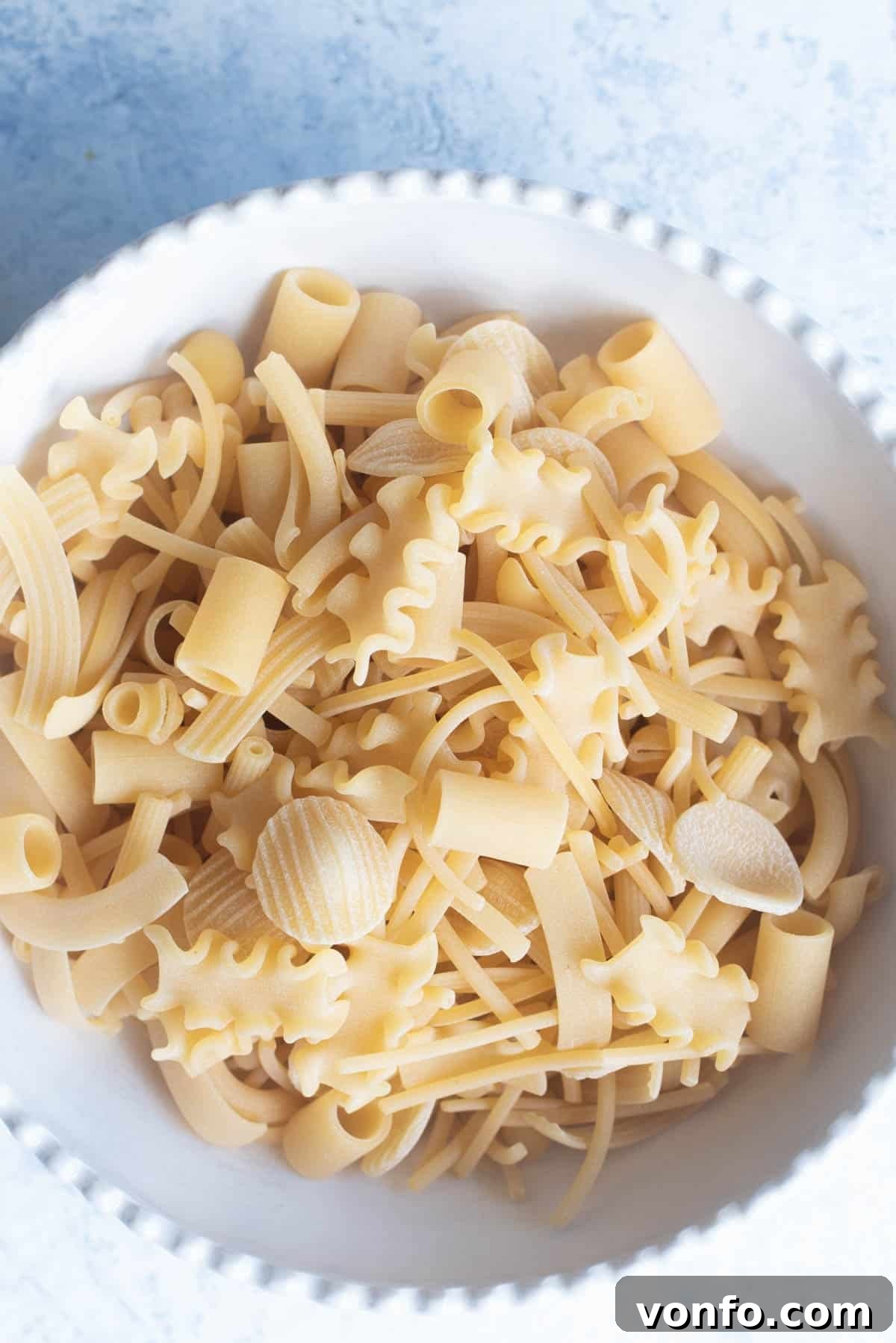 A close-up image of a bowl filled with various small pasta shapes, representing 'pasta mista'.