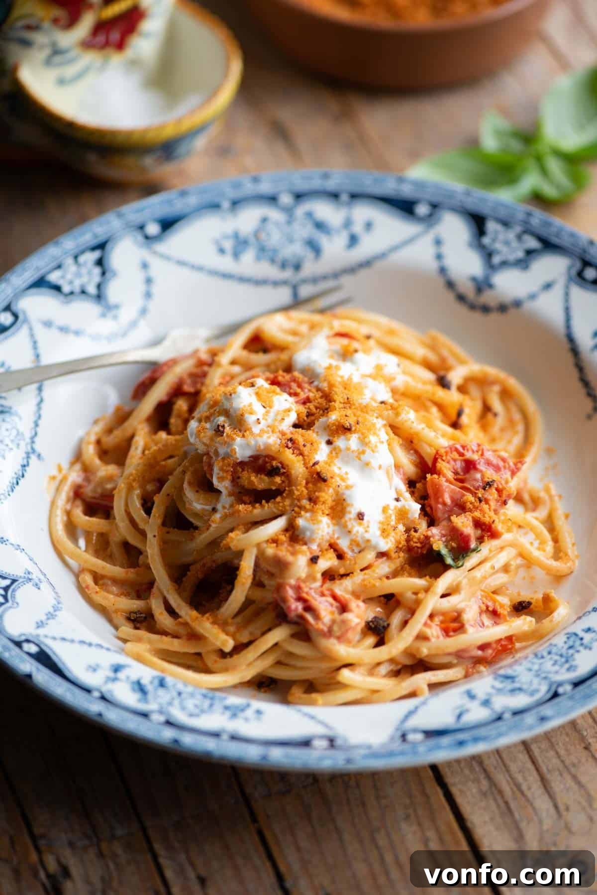 Burst Cherry Tomato Pasta with Fiery Nduja and Creamy Burrata 2 Roasted cherry tomato spaghetti in a blue bowl sitting on a wooden background, garnished with burrata and Nduja breadcrumbs.