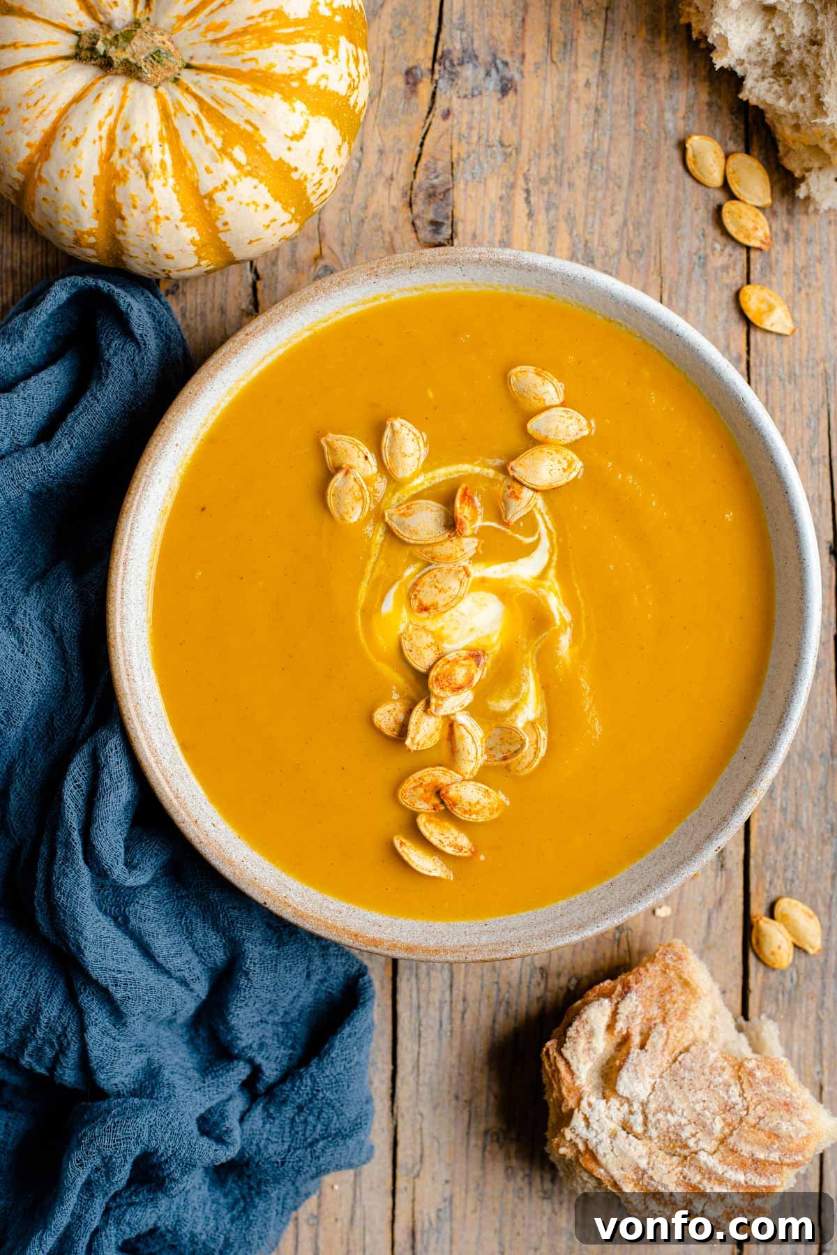 Warm Cinnamon Pumpkin Delight 2 An overhead shot of a cozy bowl of roasted pumpkin soup, beautifully garnished with toasted pumpkin seeds and a swirl of sour cream, capturing the essence of autumn comfort food.
