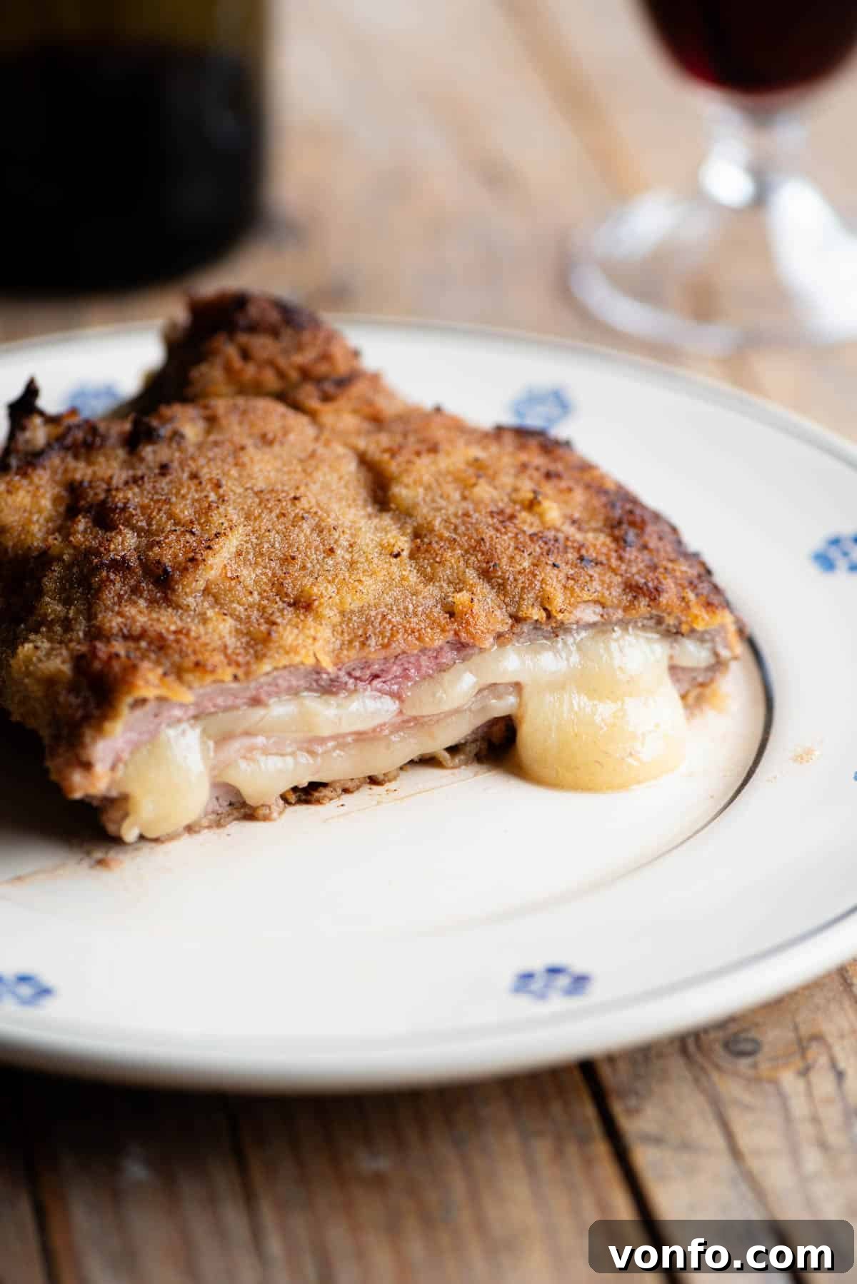 Golden Crispy Veal Stuffed with Fontina and Prosciutto 9 A stunning close-up of an Italian breaded veal chop (Costoletta Valdostana), expertly cut in half to showcase the irresistible, molten Fontina cheese and savory ham oozing from within its crispy crust.