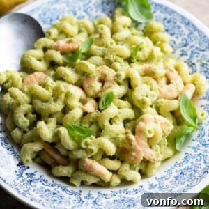 A close up of a zucchini shrimp pasta salad topped with basil.