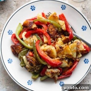 A cropped overhead shot of potatoes and peppers on a traditional Italian painted terracotta plate, representing the Pipi e Patati dish.