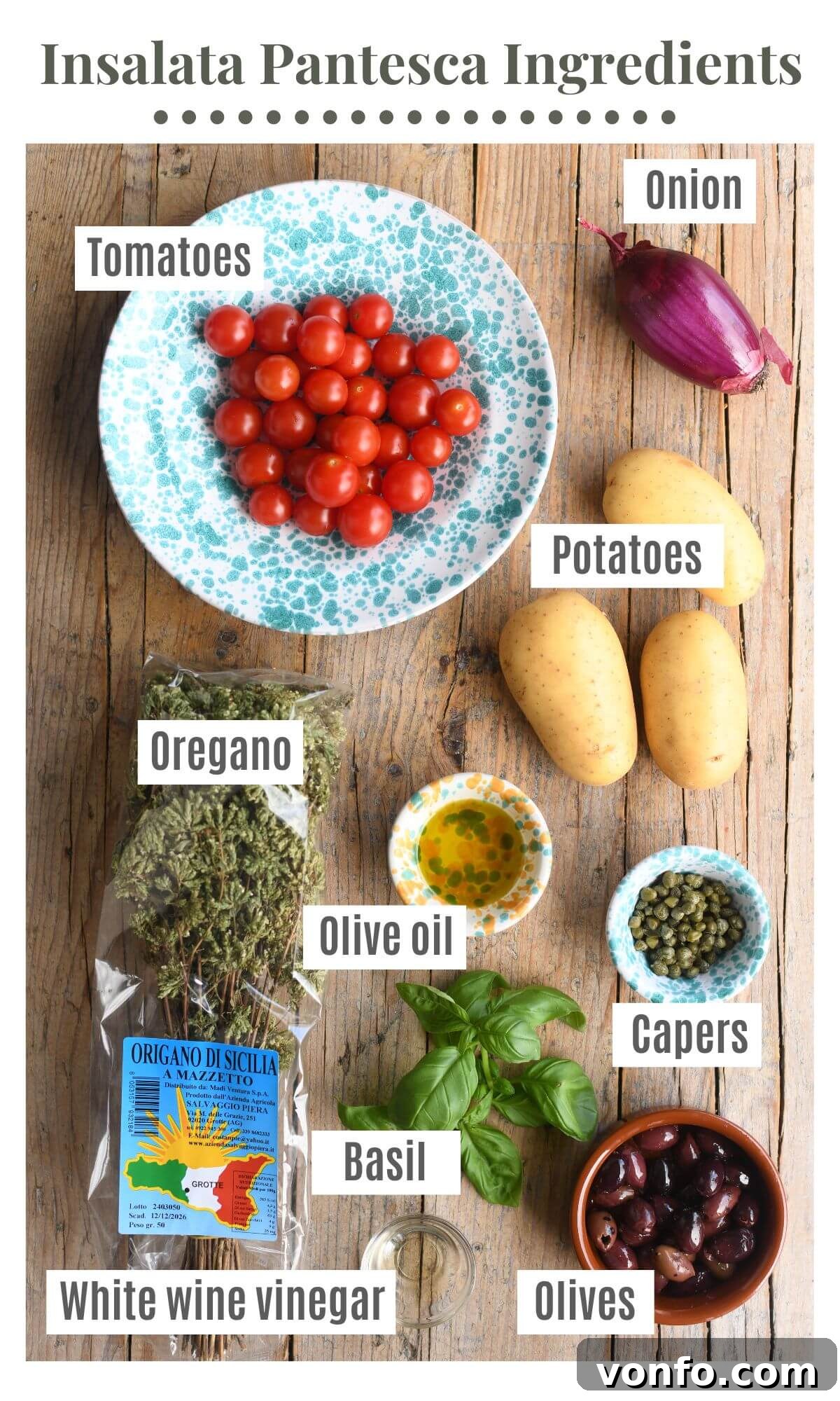 An overhead shot showcasing all the fresh and vibrant ingredients needed to prepare a traditional Sicilian potato salad, including whole potatoes, cherry tomatoes, capers, olives, red onion, fresh basil, and a bunch of dried Sicilian oregano.