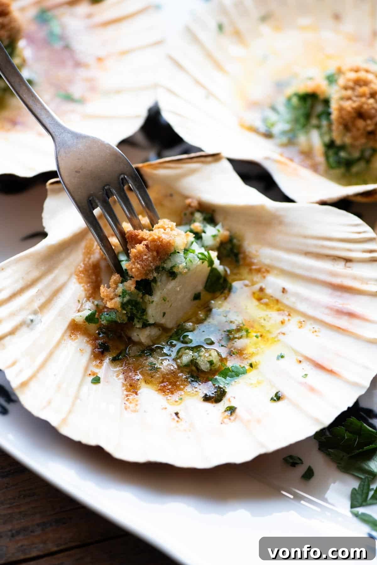 Golden Friulian Scallop Bake 5 A close up of one scallop in a shell with the golden-brown parsley butter and breadcrumb topping, and a fork inserted into the succulent scallop, ready to be enjoyed.