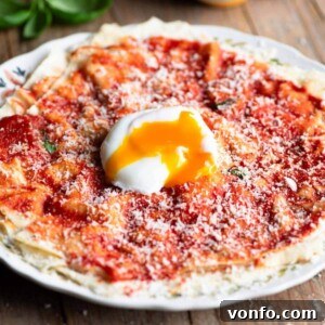 A close-up cropped image of a perfectly assembled Pane Frattau on a white plate, showcasing its appealing layers and ready for serving.