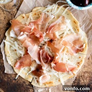 A close up cropped image of Brustengo, an Italian flatbread topped with meat and cheese, highlighting its delicious texture.